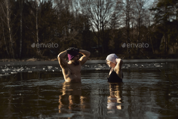 Caucasian couple standing and talking in frozen lake with hands raised - Stock Photo - Images