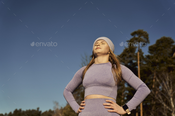 Caucasian woman taking a breath and catching sunbeams outdoors in the winter - Stock Photo - Images