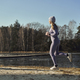 Full length of adult caucasian woman jogging on beach by the lake in the winter - PhotoDune Item for Sale