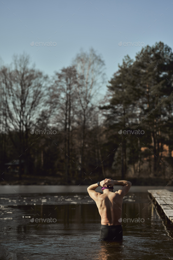 Rear view of caucasian adult man during the winter swim - Stock Photo - Images