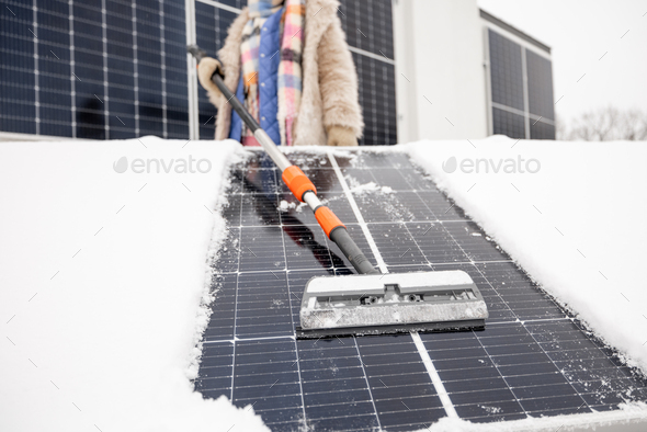 Woman cleans solar panels from snow - Stock Photo - Images