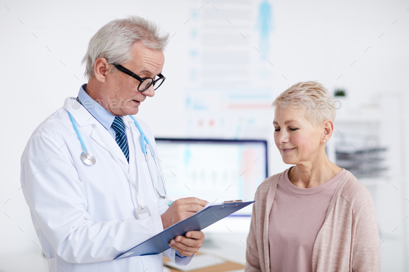 Doctor making notes while talking to patient - Stock Photo - Images