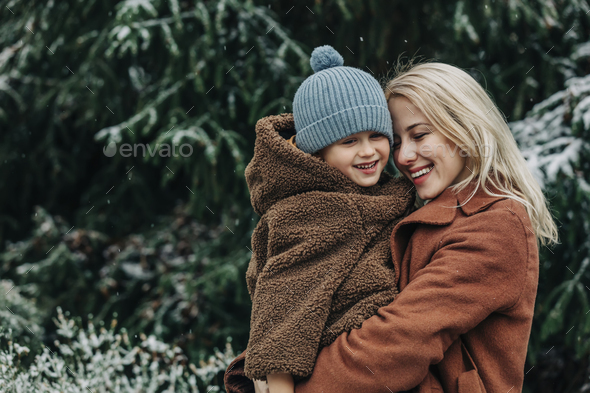 mother with son near spruce in snowy garden in winter time, P - Stock Photo - Images