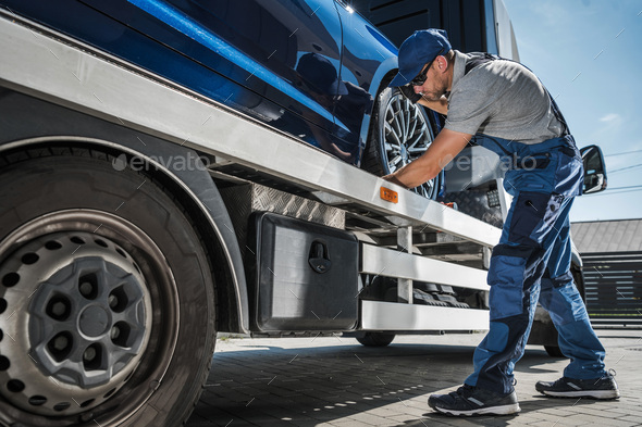 Professional Tow Truck Driver Fastening the Car for Safe Transportation - Stock Photo - Images