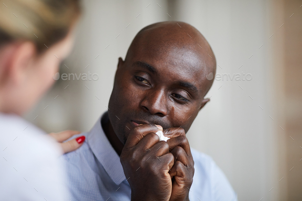Depressed black man crying at therapy session