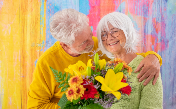 Attractive pleased elderly woman receives flowers as present for anniversary of Valentine day