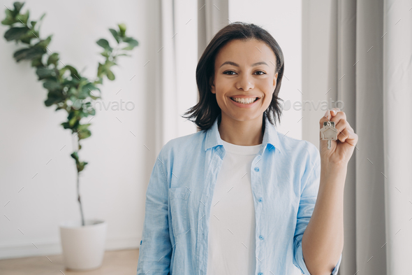 Gorgeous young lady is buying apartment and moving. Satisfied woman is holding house keychain.