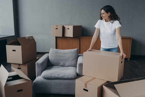 Proud single european lady in casual outfit moves. Cardboard boxes on floor. Real estate purchase. - Stock Photo - Images