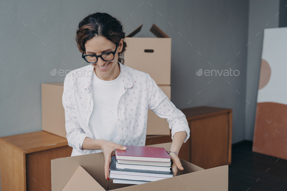Young european woman packing container and puts textbooks into. Relocation and entering to college. - Stock Photo - Images