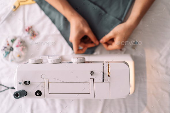 Lady fixes fabric with needles in front of a sewing machine - Stock Photo - Images