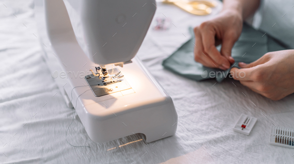 Lady fixes fabric with needles in front of a sewing machine - Stock Photo - Images