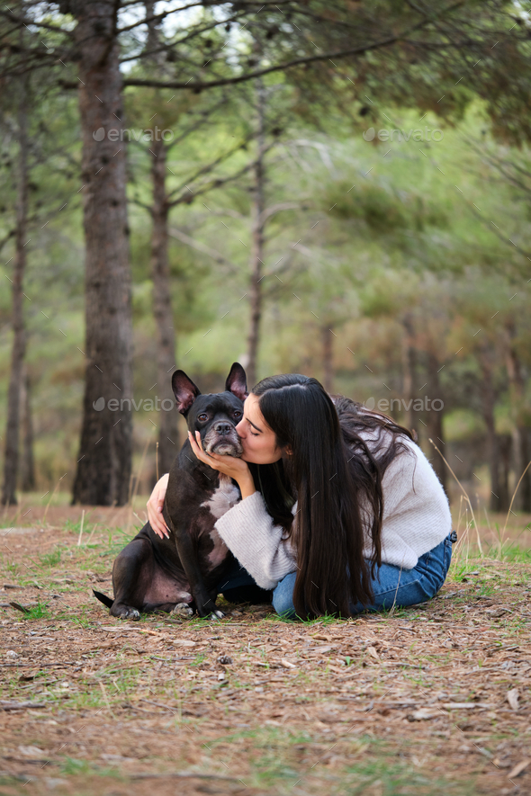 Young caucasian woman kissing her mixed breed dog at a pine forest. - Stock Photo - Images