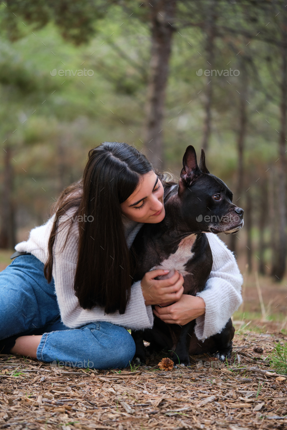 Young caucasian woman hugging her mixed breed dog at a pine forest. - Stock Photo - Images