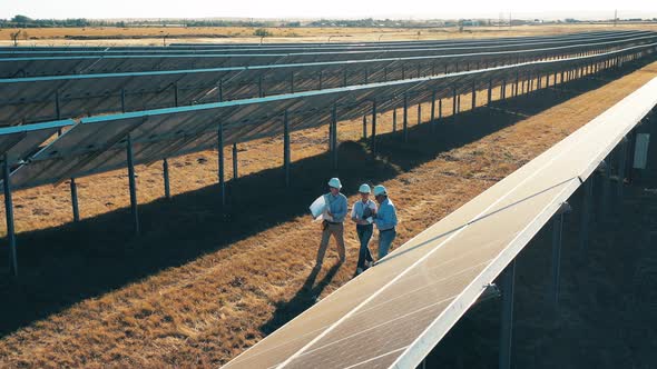 Drone Shot of Three Solar Energy Engineers Walking in a Solar Park alt
