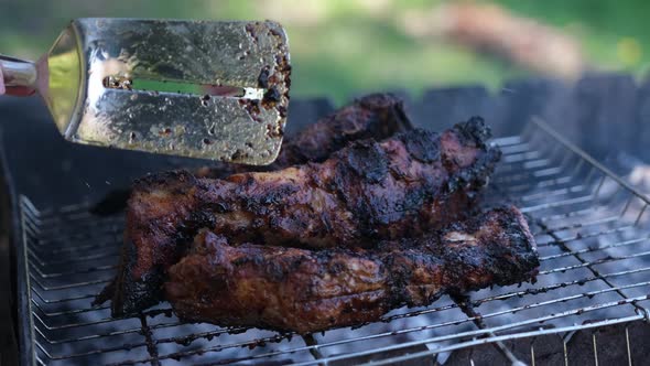 Flipping Delicious Beef or Pork Ribs Frying on a Charcoal Grill with Tongs alt