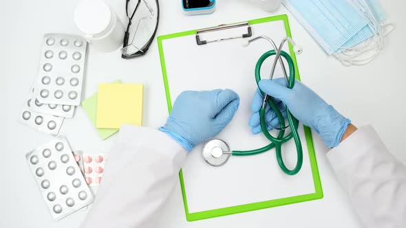 doctor in a white coat and blue latex gloves holds a medical stethoscope