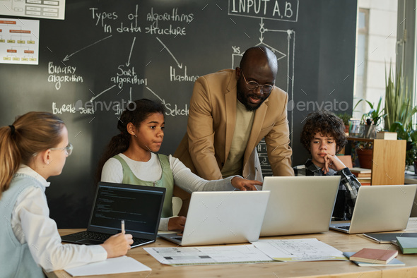 Teacher teaching students to use computers Stock Photo by AnnaStills