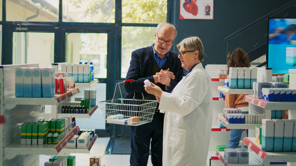 Elderly man showing prescription paper to pharmacist - Stock Photo - Images