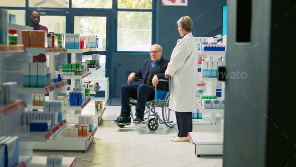 Pharmacist giving cardiology pills bottle to senior wheelchair user - Stock Photo - Images
