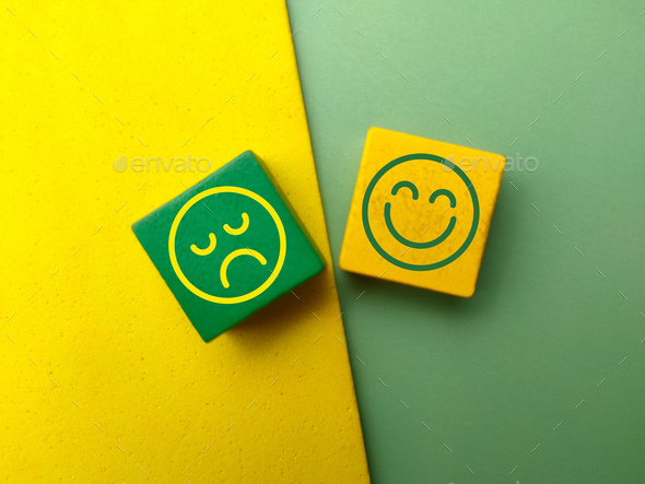Top view colored wooden cube with the happy and unhappy face icons.