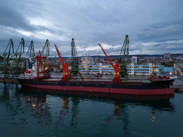 Aerial view of cargo ship bulk carrier is loaded in port at sunset ...