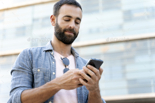 Latin man holding smartphone chatting, check email, reading news, shopping online