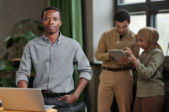 Young confident business leader in smart casualwear standing by workplace - Stock Photo - Images