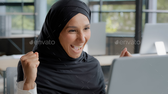 Young excited arab woman checking email on laptop concentration reading gets good news amazed happy