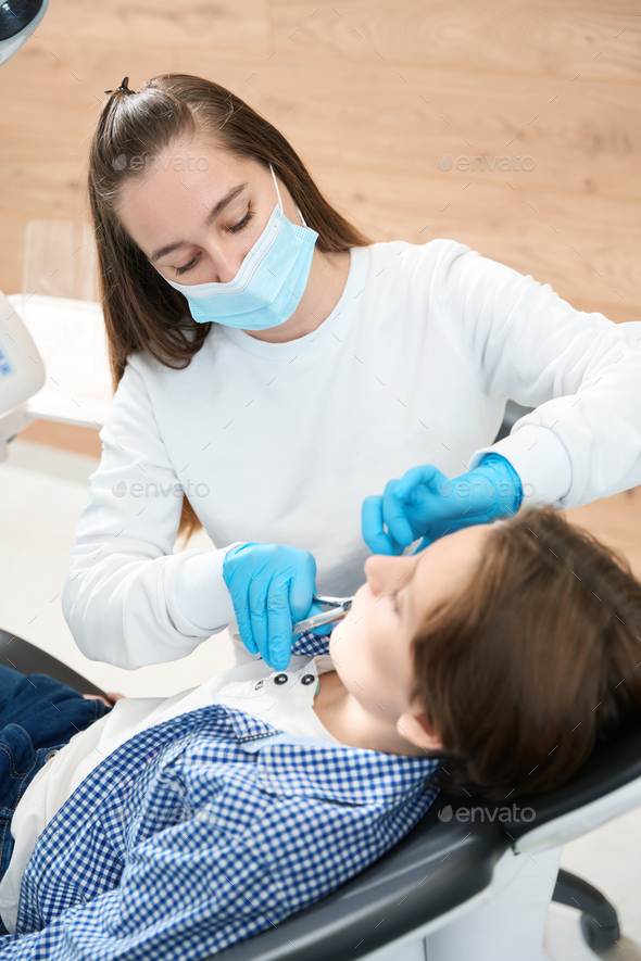 Dentist surgeon removes a tooth to boy with special tool Stock Photo by
