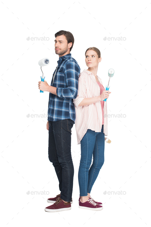 couple with paint rollers standing back to back isolated on white background