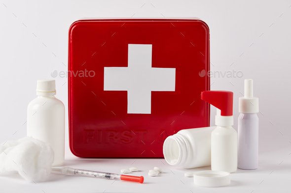 first aid kit box with blank medical bottles, syringe and cotton swab on white