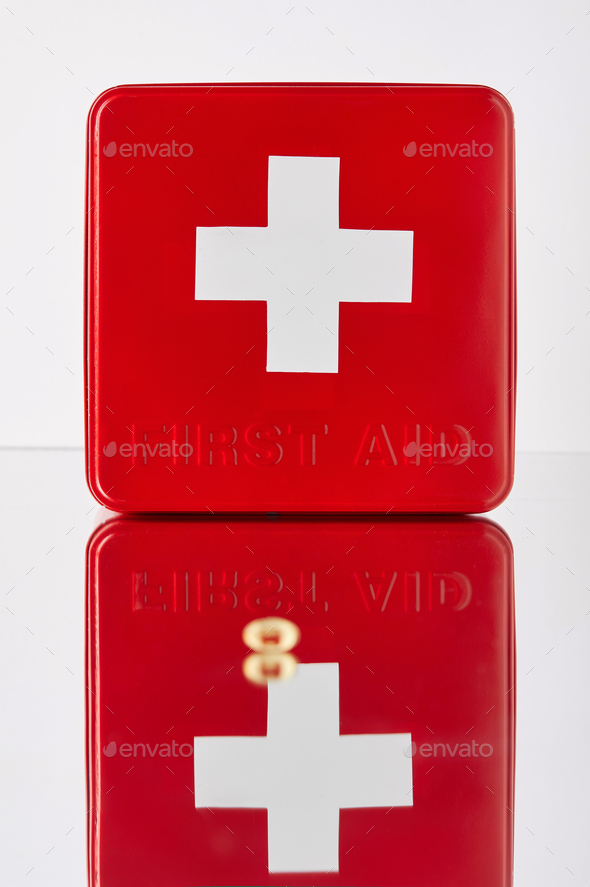 red first aid kit box with omega capsule on reflective surface