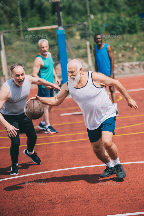 interracial elderly sportsmen playing basketball together on playground