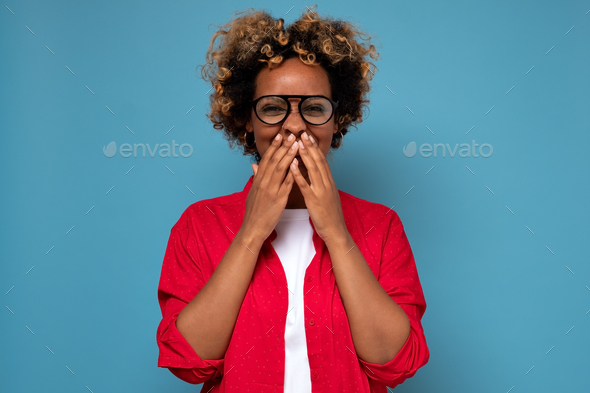 African American woman with curly hair laughing and embarrassed giggle covering mouth with hands
