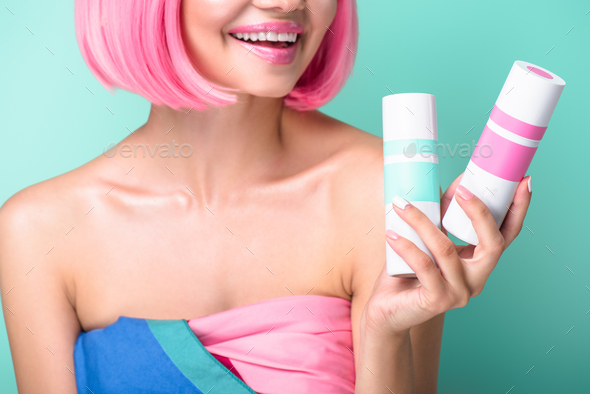 cropped shot of young woman with pink bob cut holding cans of coloring hair sprays isolated on