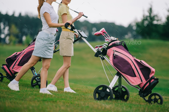 partial view of female golf players in polos walking on golf course