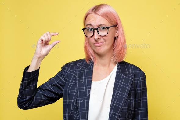 Caucasian woman showing small amount of something with fingers. - Stock Photo - Images