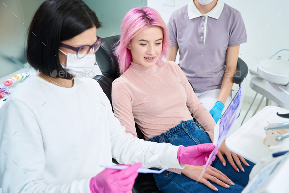 Young woman is looking at pictures teeth with her orthodontist - Stock Photo - Images