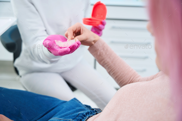 Woman takes transparent cap from the hands of an orthodontist - Stock Photo - Images