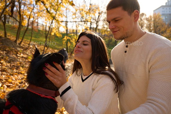 Young cheerful couple walking their dog in the park - Stock Photo - Images