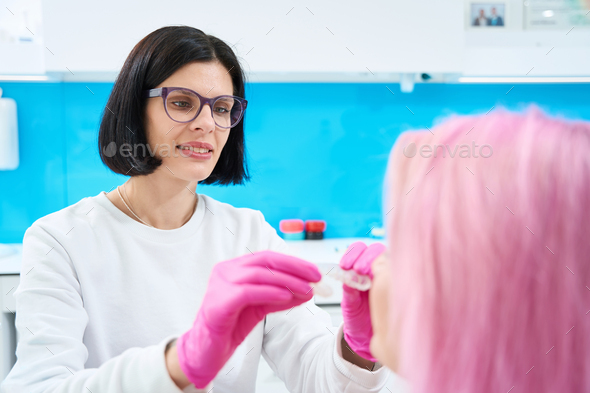 Woman orthodontist holds a transparent cap in her hands - Stock Photo - Images