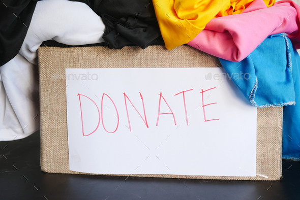 Donation box with donation clothes on a wooden table .