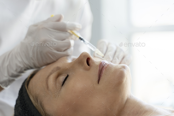 Senior woman relaxing during facial mesotherapy for smoothing of mimic wrinkles