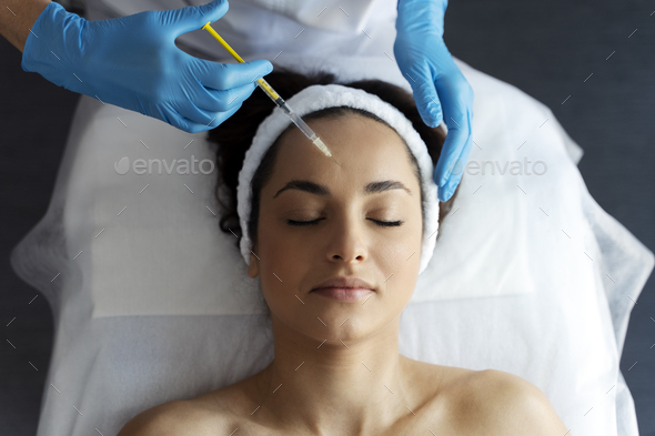 Beautiful woman during facial mesotherapy for smoothing of mimic wrinkles with beautician