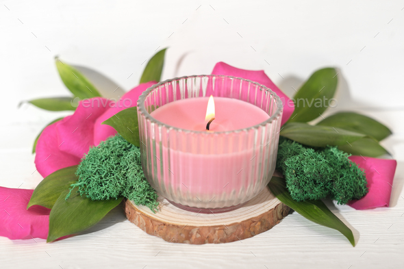 pink soy wax candle burning on a wooden saw cut podium with floral decor. Valentines day decoration - Stock Photo - Images