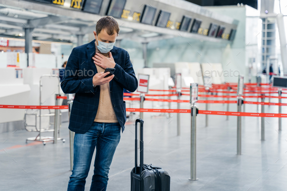 Businessman walks in airport terminal, has problems with breathing checks email box