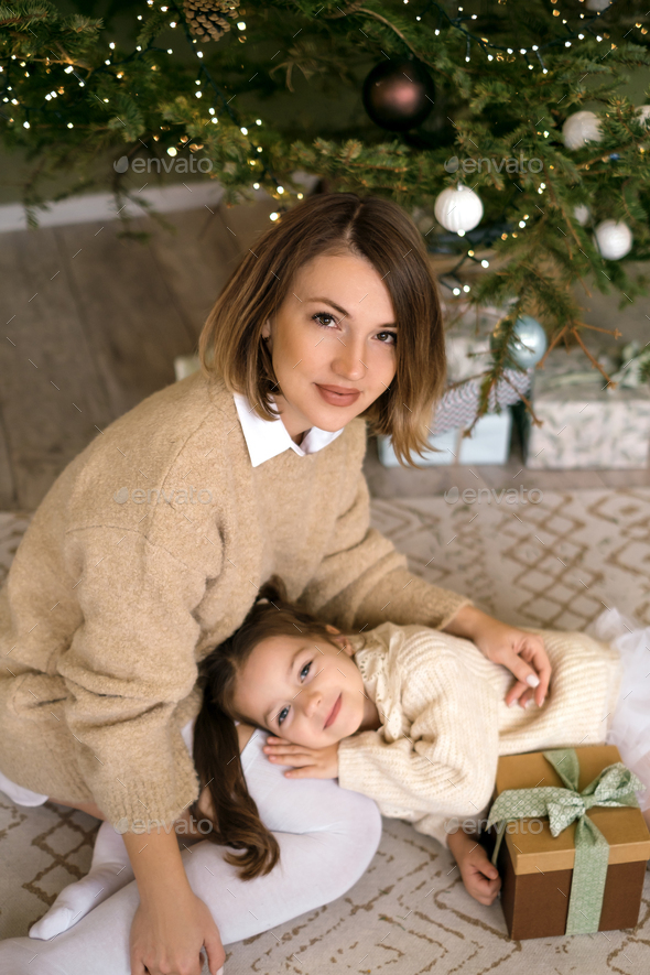Kid is lying on mother's lap under the Christmas tree - Stock Photo - Images