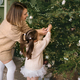 Mom and girl in beige sweater decorate Christmas tree - PhotoDune Item for Sale