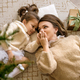 Mom kisses daughter&#39;s hands lying under Christmas tree - PhotoDune Item for Sale