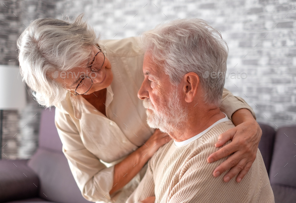 Old worried senior woman comforting her depressed, mental ill husband, unhappy elderly man